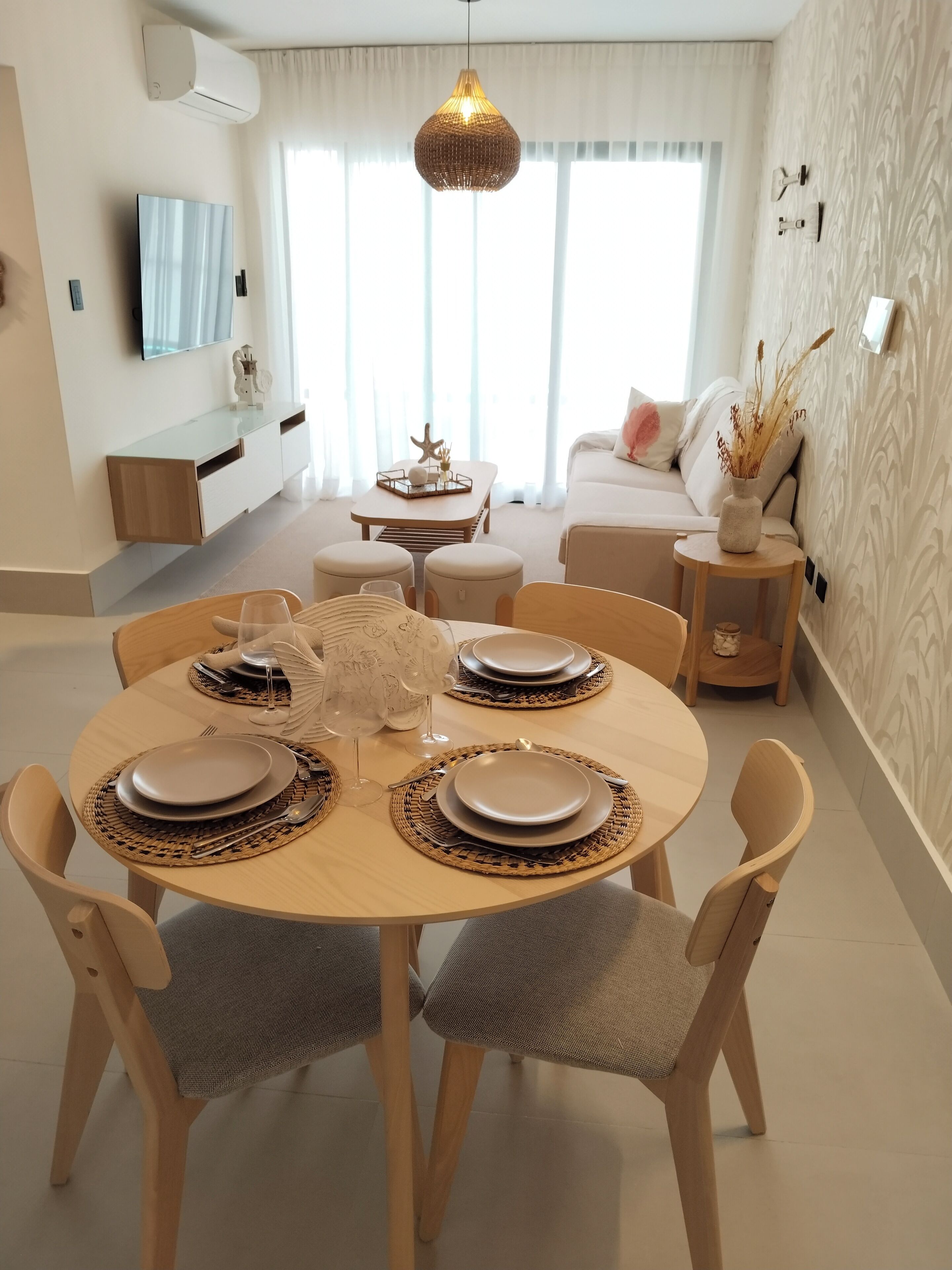 Een eetgedeelte met een ronde tafel gedekt voor vier personen, omringd door houten stoelen.