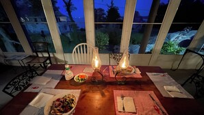 Una mesa de comedor para dos personas, con platos de comida, una botella y una vela encendida.