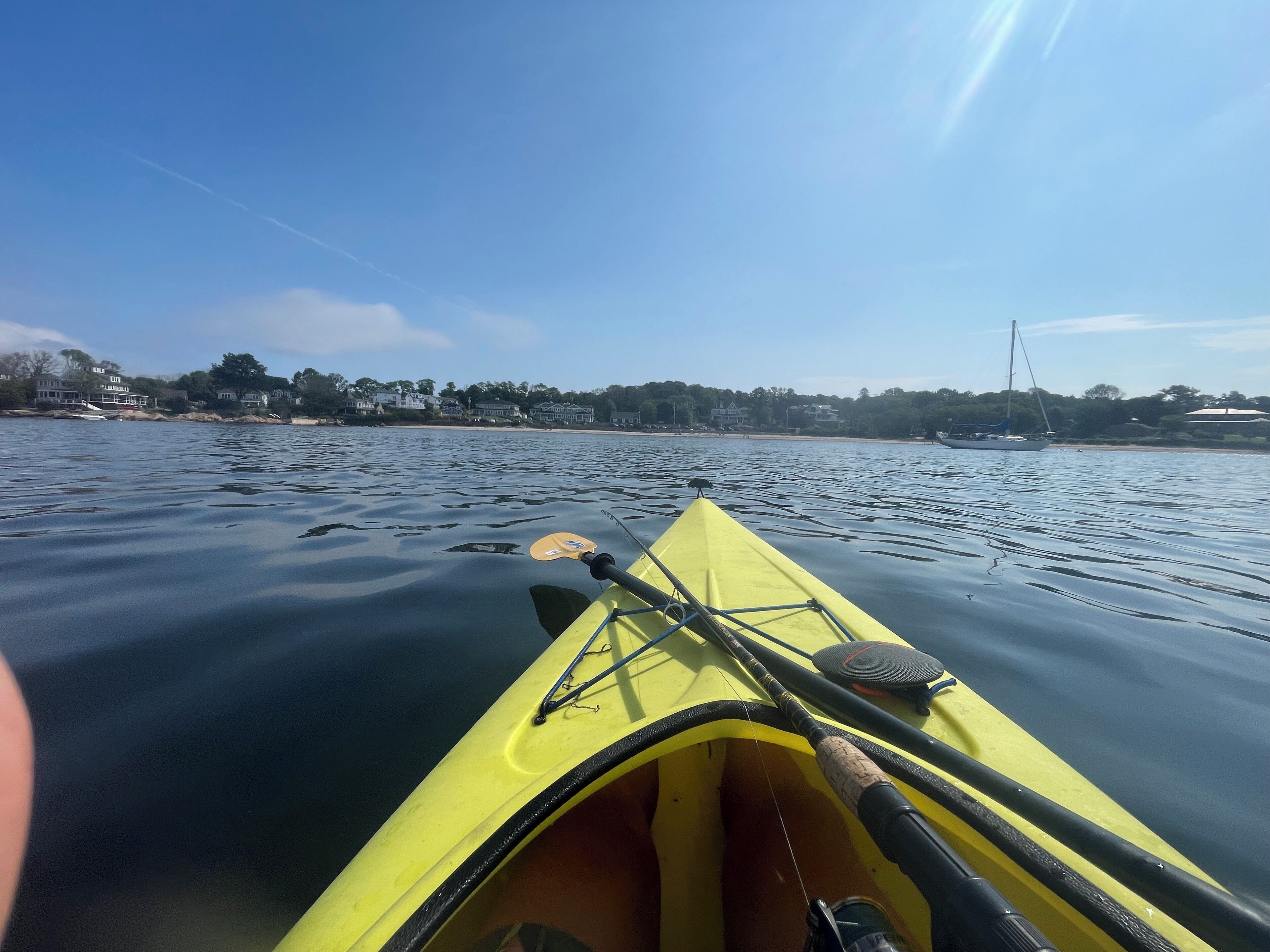 Un kayak sur une eau calme, avec une canne à pêche et une pagaie.