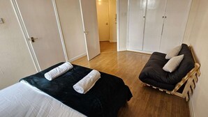 A bedroom with a bed, a wooden chair with cushions, and a wardrobe.