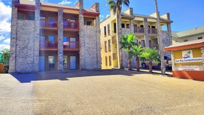 A multi-story building with balconies, palm trees, and a sign for Sun Ray Condominiums.