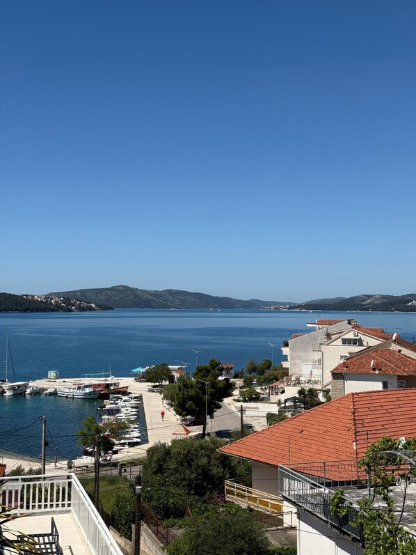 A coastal town with a marina, buildings with red-tiled roofs, and a clear view of the sea.