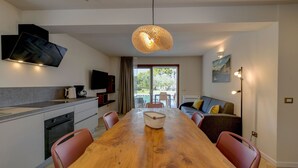 A modern kitchen with a wooden dining table, red chairs, and a hanging light fixture. - Gardaliva 7 by the lake in Manerba (Manerba del Garda)