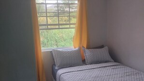 Ein Schlafzimmer mit Bett, Vorhängen, einem Fenster und einer Klimaanlage.