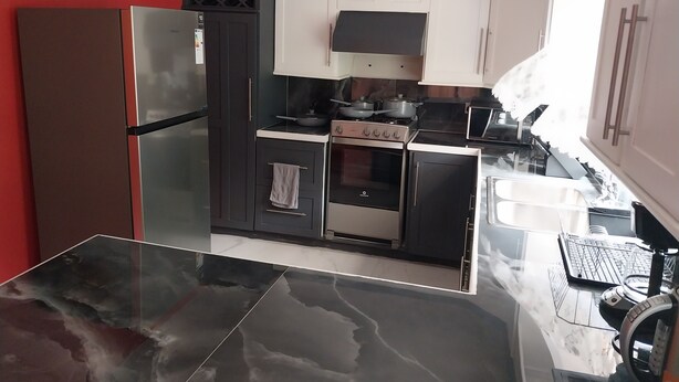 Eine moderne Küche mit Kühlschrank, Herd, Backofen und Mikrowelle.