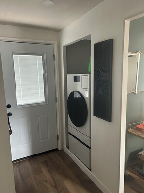 A hallway with a white door, a wall-mounted air conditioning unit, and a mirror.