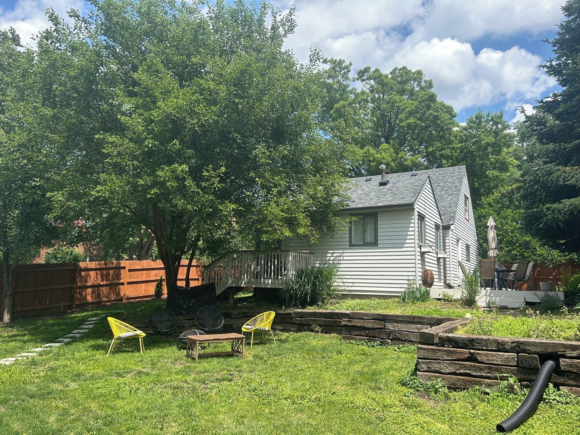 A house with a deck, a lawn, and a tree.