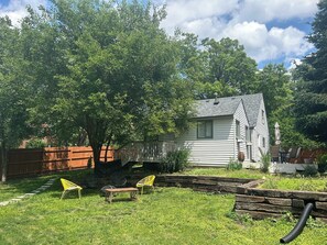 A house with a deck, a lawn, and a tree.