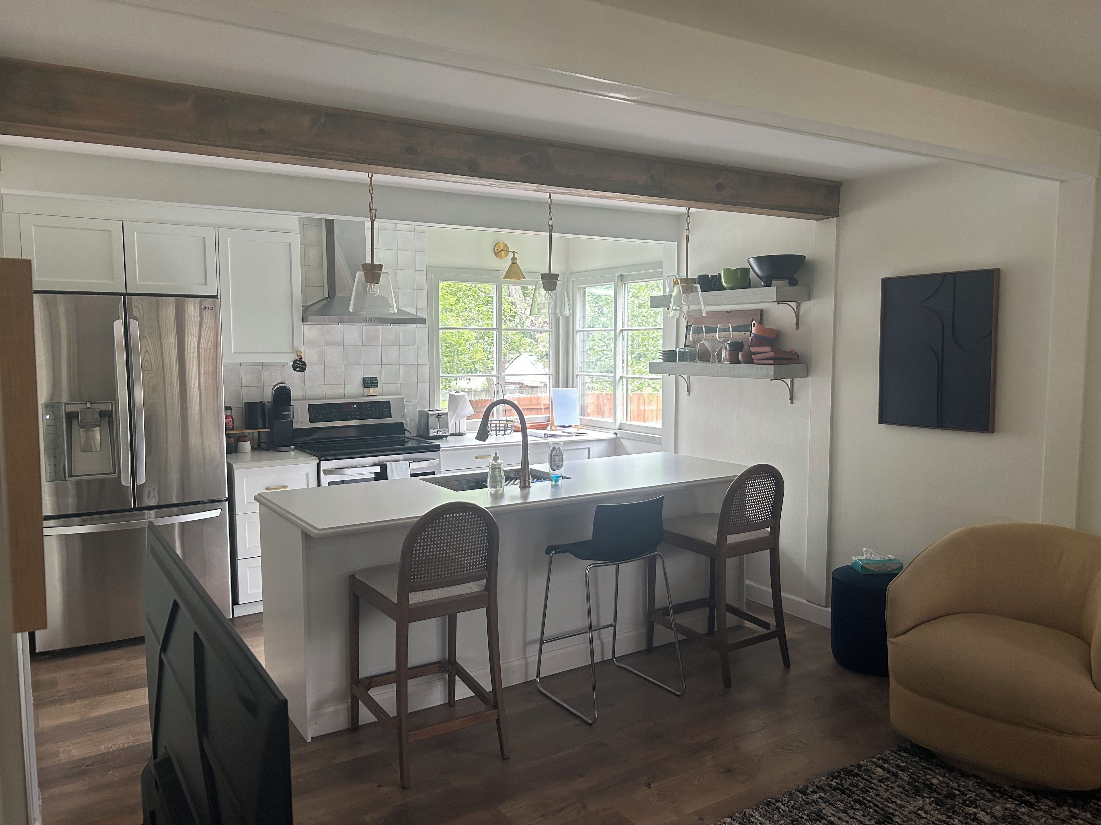 A modern kitchen with a central island, bar stools, and a dining area with a chair.