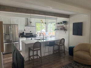 A modern kitchen with a central island, bar stools, and a dining area with a chair.