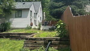 A residential backyard with a house, a wooden fence, and a grassy area.