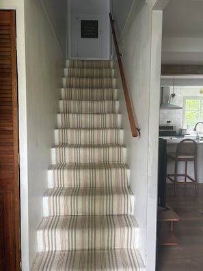 A staircase with striped carpet leading to a door with a plaque.