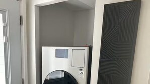 A compact, modern room with a built-in washer-dryer unit, a door, and a textured wall piece.
