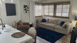 A living room with a sofa, a dining table, and a TV.