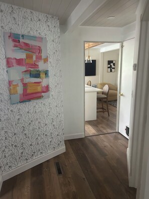 A hallway with a wooden floor, a white door, and a wall with floral wallpaper.
