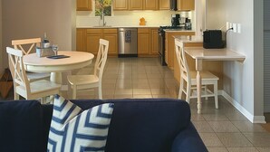 Una cocina moderna con armarios de madera, horno integrado y un comedor con mesa y sillas redondas.