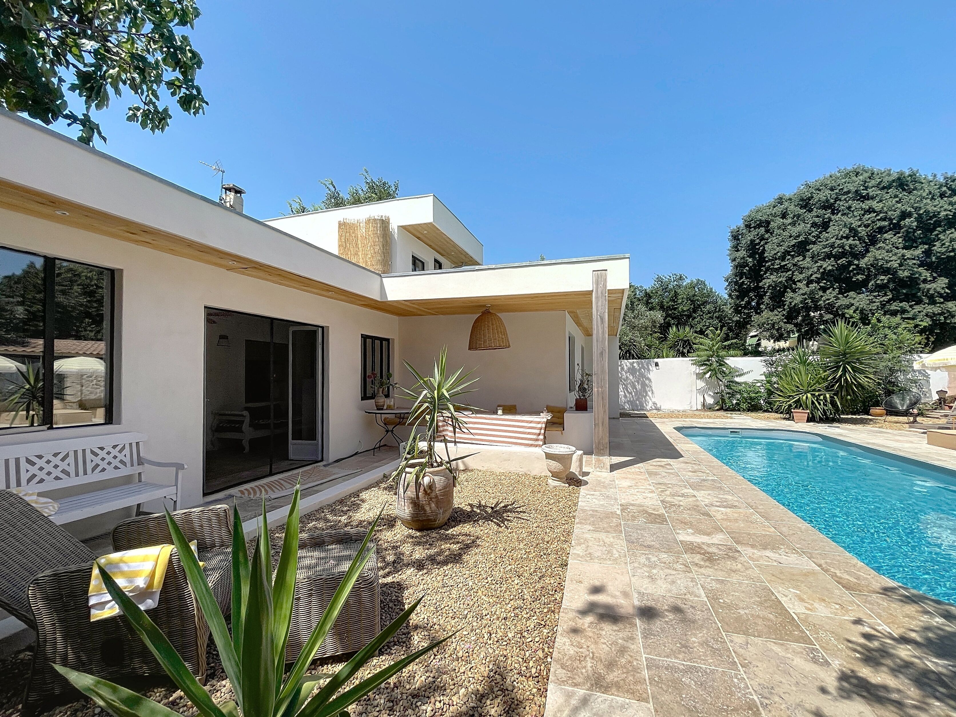 A modern house with a pool, outdoor seating, and a covered patio area.