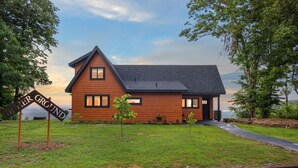 Una casa moderna con techo inclinado, revestimiento de madera y un pequeño porche delantero.