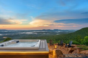 A hot tub on a wooden deck with chairs and a fire pit, overlooking a mountainous landscape. - Spectacular Arkansas Grand Canyon With Hot Tub (Jasper)
