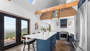 Una cocina moderna con una isla grande, electrodomésticos de acero inoxidable y vistas al exterior.