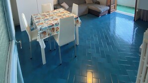 Une pièce comprenant une table à manger, des chaises, un canapé et un luminaire au plafond.