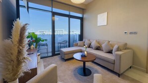 A modern living room with a sofa, armchairs, a coffee table, and a large window offering a city view.