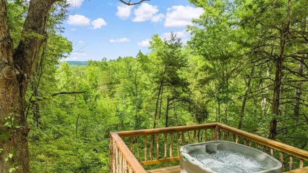A hot tub on a wooden deck surrounded by lush green forest.