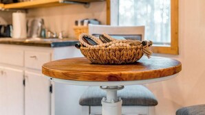 A kitchen with a wooden table, a woven basket, and a window with a view of trees.