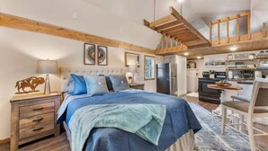 A bedroom with a bed, bedside tables, a lamp, and a wooden ceiling.