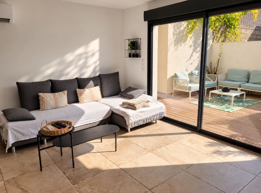 Een moderne slaapkamer met een groot bed, een bankje, een kleine tafel en een schuifdeur naar een terras.