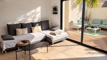 Een moderne slaapkamer met een groot bed, een bankje, een kleine tafel en een schuifdeur naar een terras.