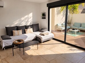 Een moderne slaapkamer met een groot bed, een bankje, een kleine tafel en een schuifdeur naar een terras.