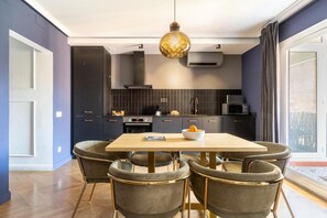 Eine moderne Küche mit dunklen Schränken, einem Holztisch und vier Stühlen.