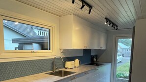 Eine moderne Küche mit einem großen Fenster, weißen Schränken und einer Edelstahlspüle.