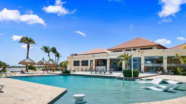 A resort pool area with lounge chairs, a bar, and a restaurant. - NEW 2BR/2BA w/Private Jacuzzi minutes from beaches. Gym/Pools/Tennis/Restaurant (Noord)