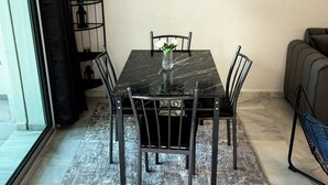 Un comedor con una mesa de mármol, sillas negras, un tapete y tres cuadros en la pared.