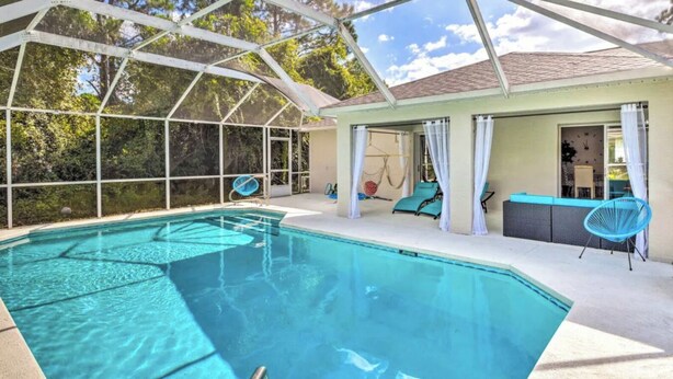 Une piscine entourée de parois en verre, un espace détente avec des fauteuils et une vue sur les arbres.