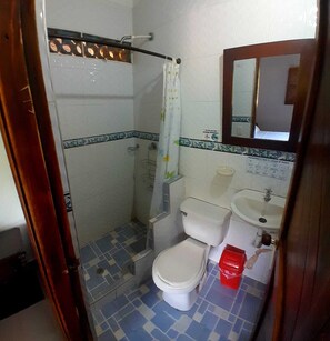 A small bathroom with a shower, toilet, and sink.