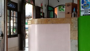 Un área de recepción con mostrador, pared verde con cartel y suelo de baldosas.