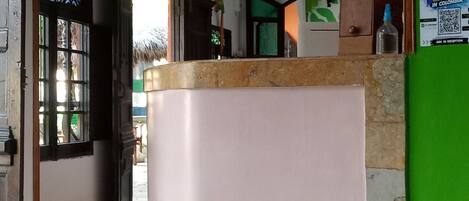 A reception area with a counter, a green wall with a poster, and a tiled floor.