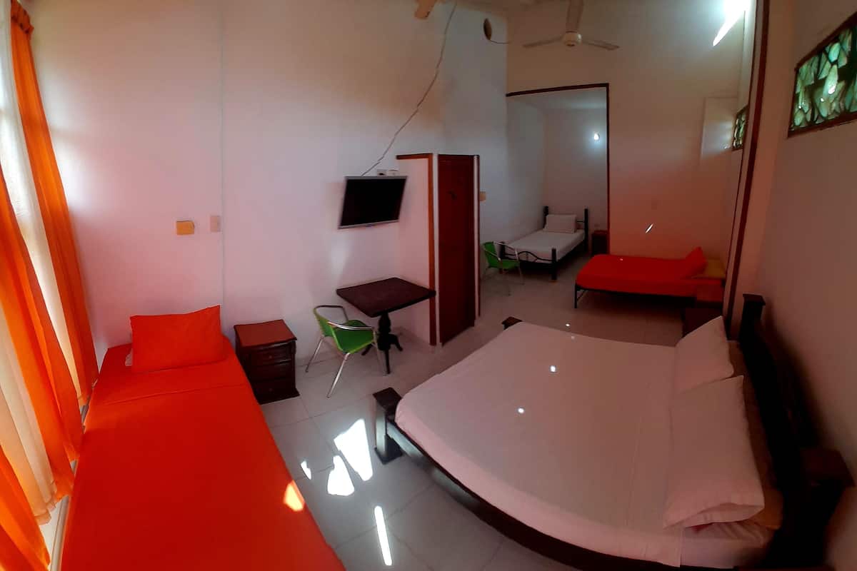 Une chambre comprenant un grand lit, un bureau, une chaise, un téléviseur et une porte donnant sur une autre pièce.