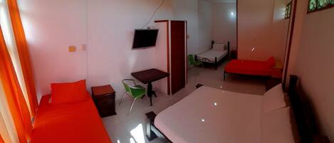 Una habitación con una cama grande, un escritorio, una silla, un televisor y una puerta que da a otra estancia.