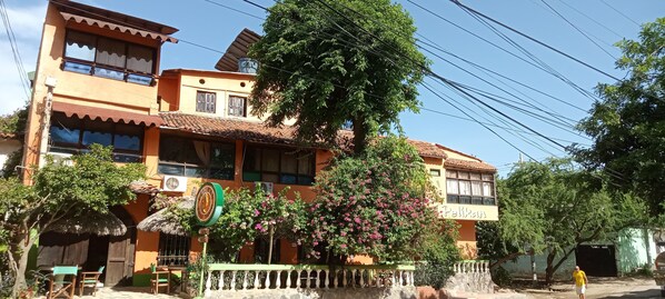 A two-story building with a balcony, a clock, and a sign that reads "Pelikan."
