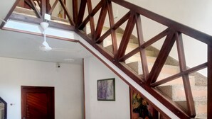 Una sala de estar con un sofá blanco, una mesita de centro blanca y una escalera de madera.