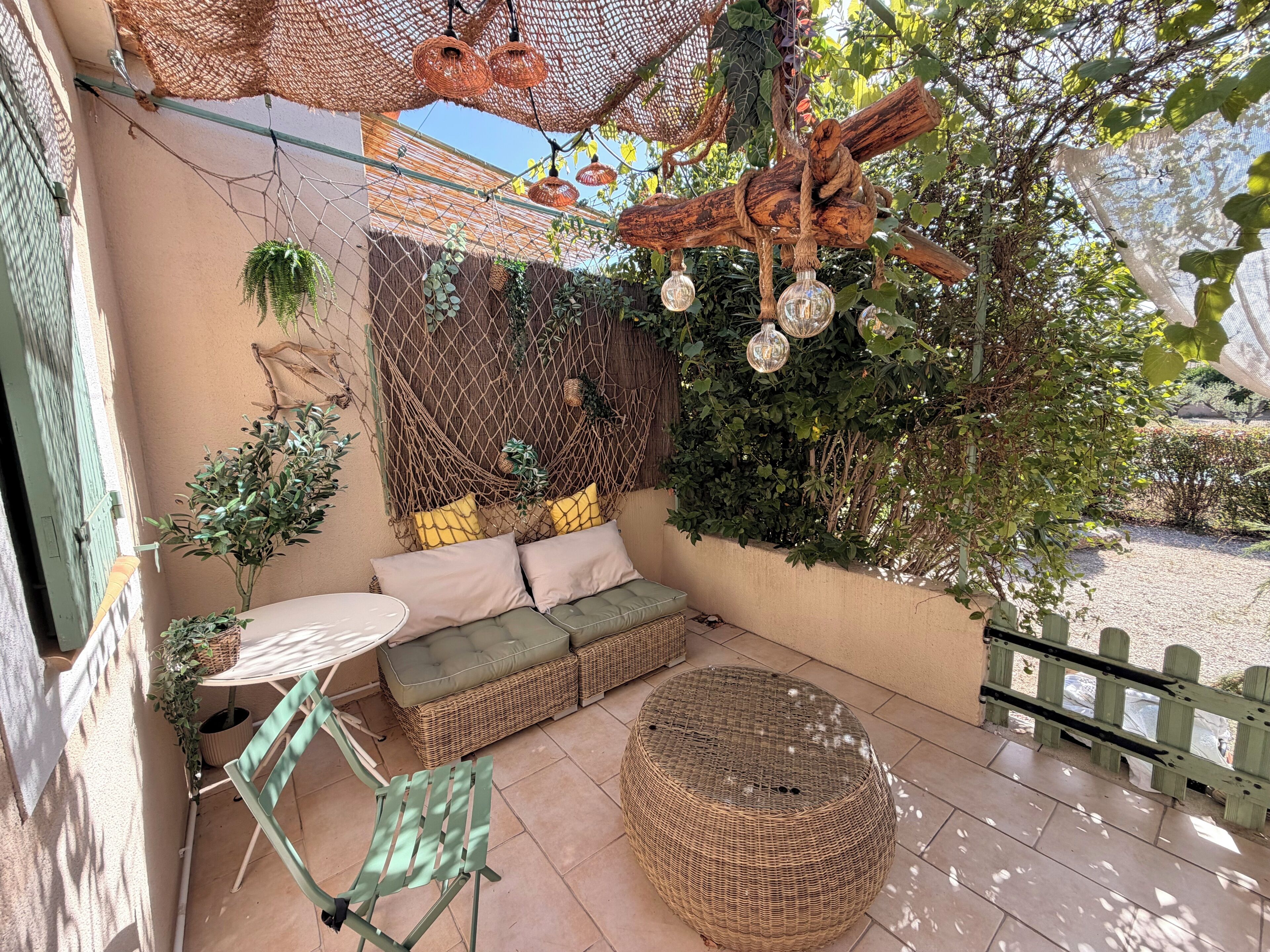 A cozy outdoor seating area with a wicker sofa, a round ottoman, and a small table.