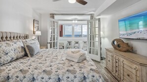 Ein Schlafzimmer mit Bett, Deckenventilator, großem Fenster und Meerblick.