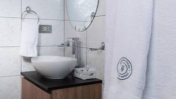Un baño moderno con lavamanos blanco, tocador de madera y un espejo grande.