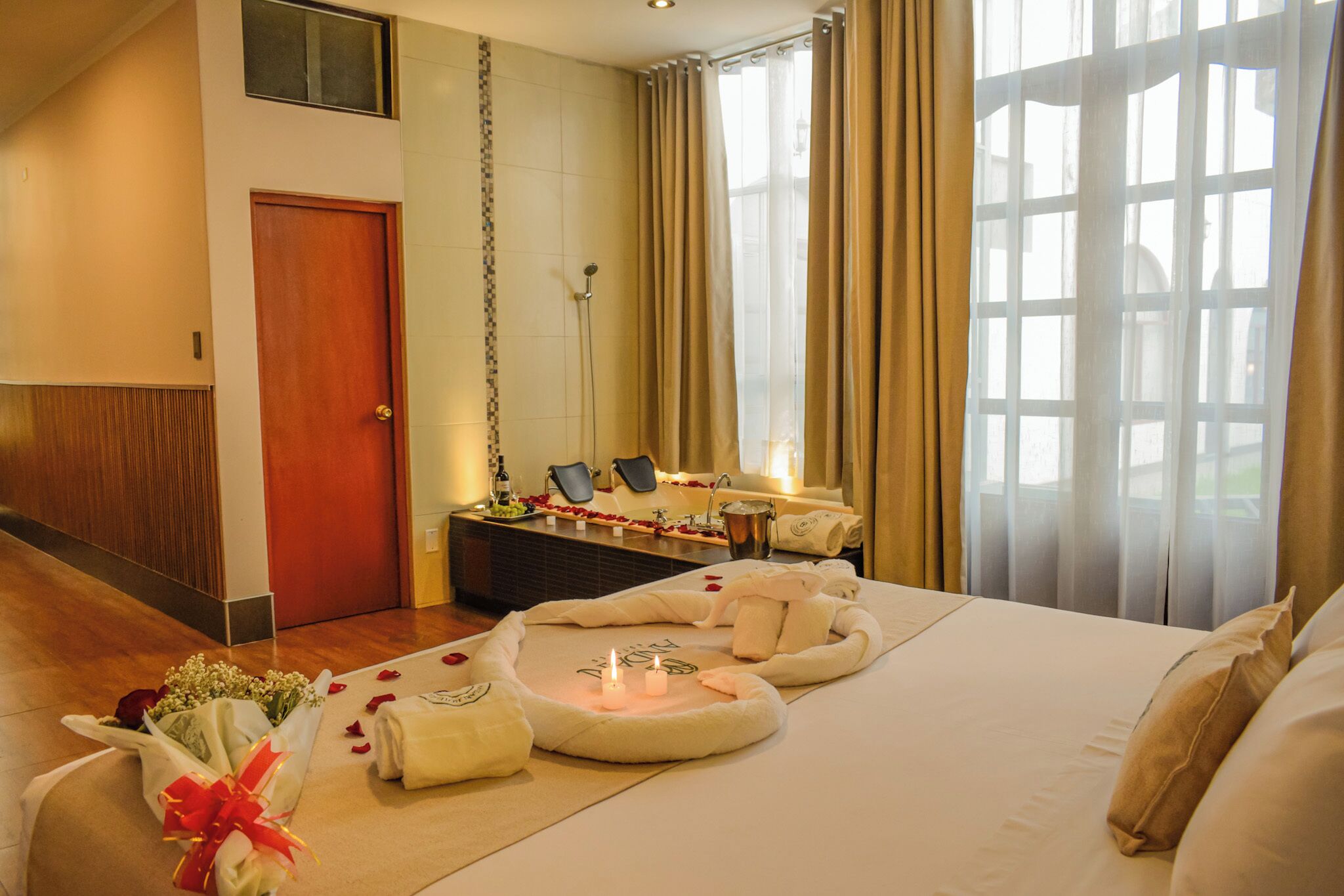 Ein Hotelzimmer mit Bett, Badezimmer mit Dusche und Fenster mit Vorhängen.