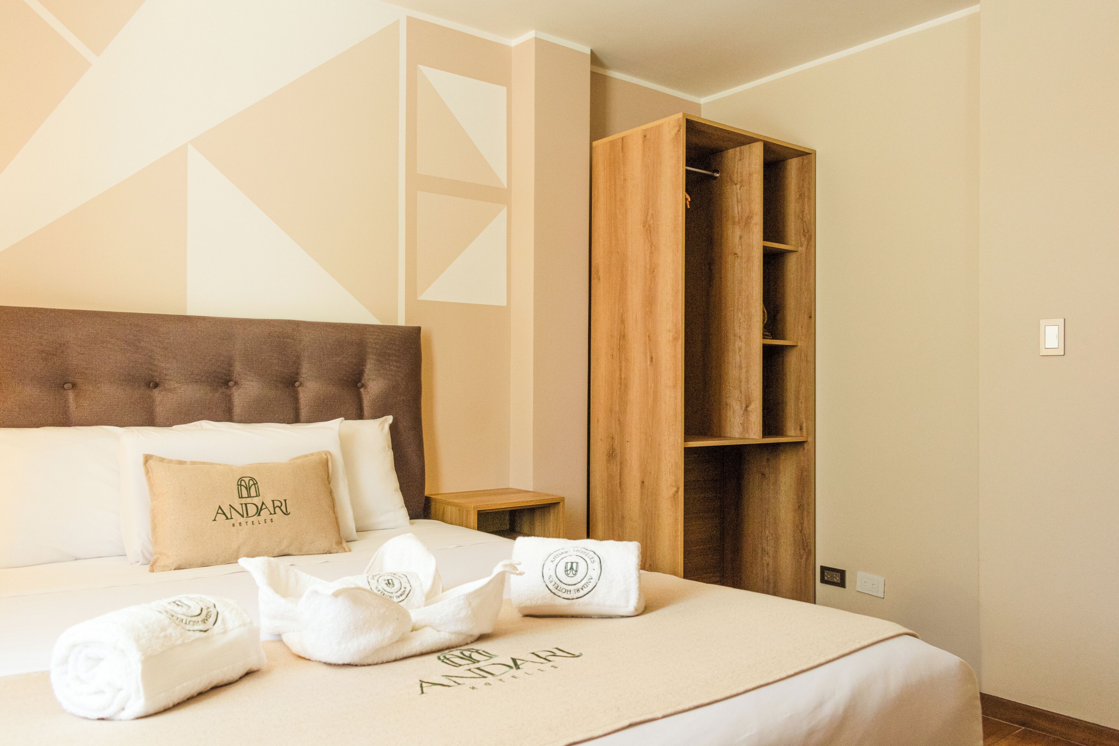 Una habitación de hotel con cama, armario de madera y mesita de noche.
