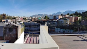 A rooftop terrace with a view of a cityscape and mountains in the distance. - ANDARI HOTELES (Arequipa)